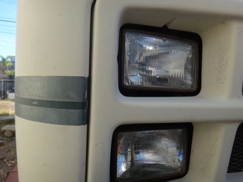 1995 Chevrolet P30 1 Ton - Step Van - Close-up view of the front headlights on a white step van. The headlights are rectangular and stacked vertically, with a dark trim around t…