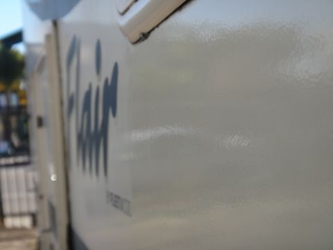 1995 Chevrolet P30 1 Ton - Step Van - A close-up, side view of a cream-colored vehicle shows the word "Flair" in large, dark blue lettering. The vehicle appears to be a step van…