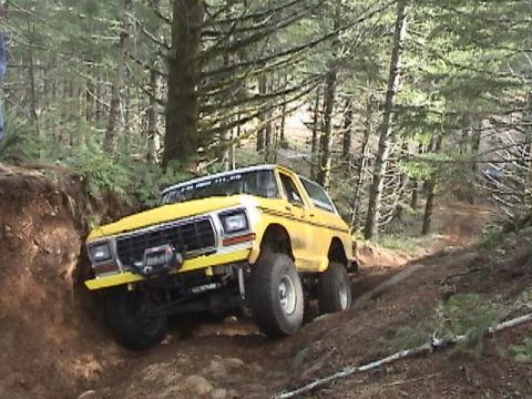1994 Ford Explorer - This lifted 1979 Ford Bronco navigates a steep, wooded trail with its front wheels angled towards a dirt embankment.