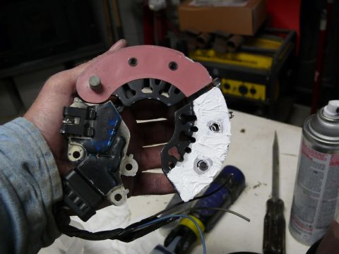 Car alternator part with pink and black housing, wires, and white paste.