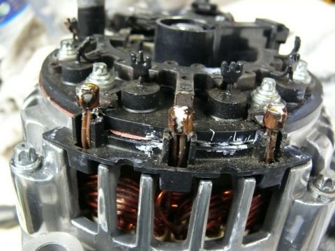 Close-up of automotive alternator internals with copper windings and terminals.