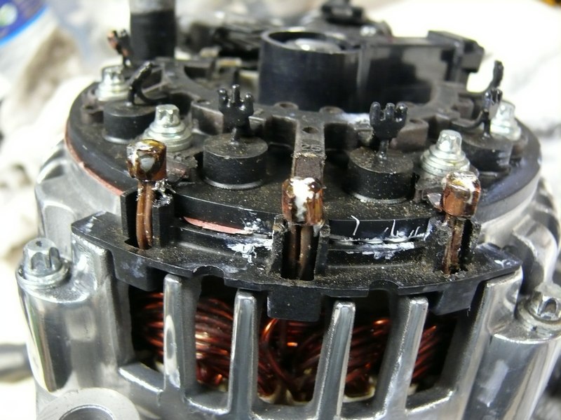 Close-up of automotive alternator internals with copper windings and terminals.