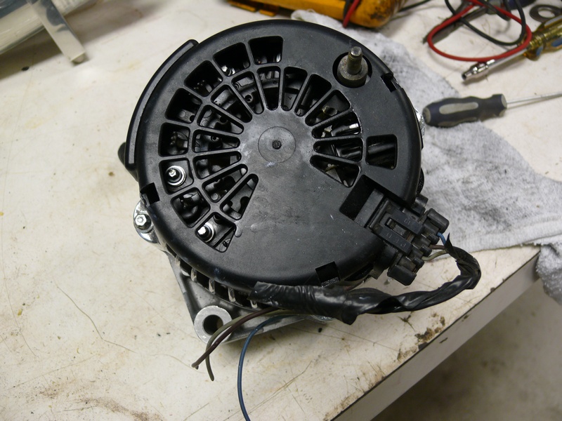 Close-up of a car alternator with black plastic housing and silver metal base.