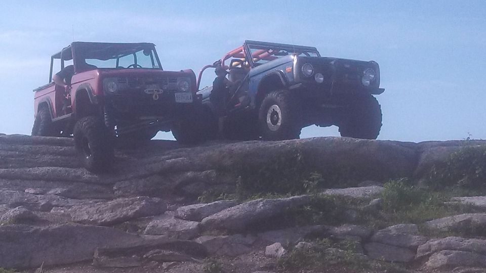 Two modified Ford Broncos on a rocky incline.