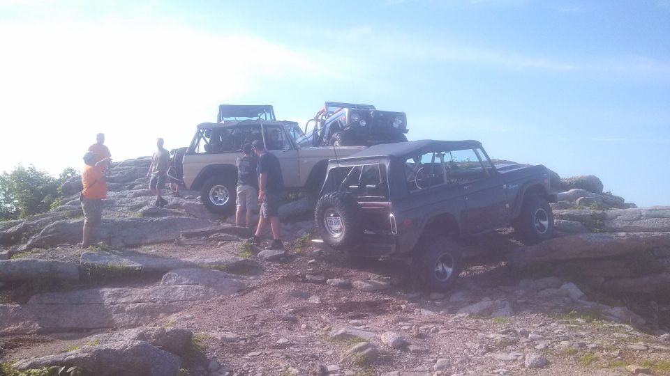 Several Ford Broncos parked on a rocky hill.