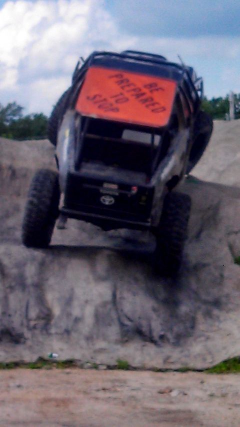 1979 Ford Bronco - A lifted off-road vehicle, possibly a custom build, is shown climbing a steep, rocky incline. The rear of the vehicle displays an orange si…