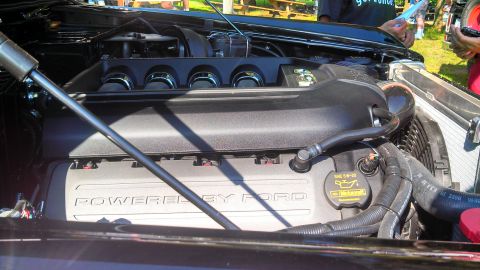 1979 Ford Bronco - Close-up view of a Ford engine bay, featuring a black engine cover with chrome accents and "POWERED BY FORD" text visible on a silver compo…