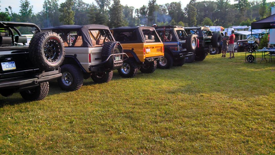 Several Ford Broncos parked in a grassy field.