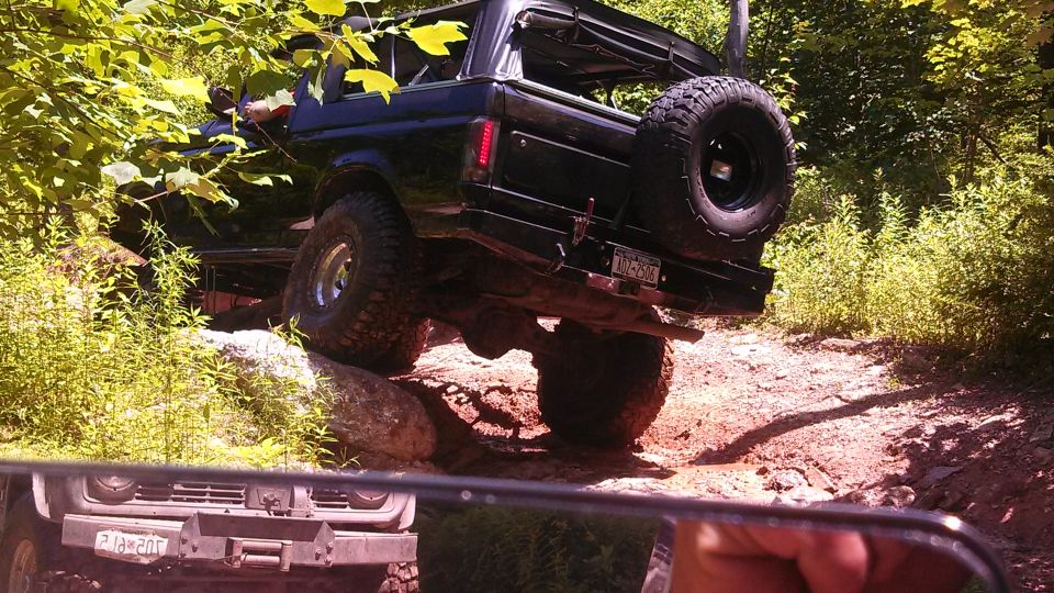Black Ford Bronco off-roading on a muddy, rocky trail.
