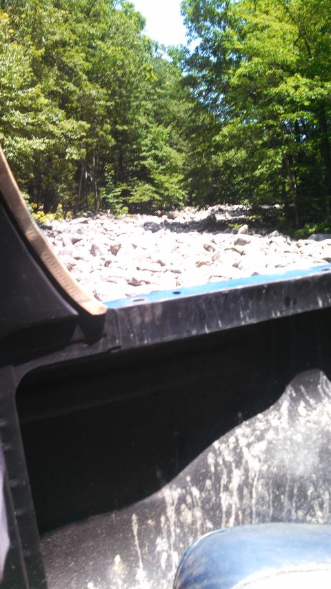 1979 Ford Bronco - The interior of a vehicle, possibly a truck bed, is shown with a rocky, wooded area visible in the background. The vehicle's dark interior…