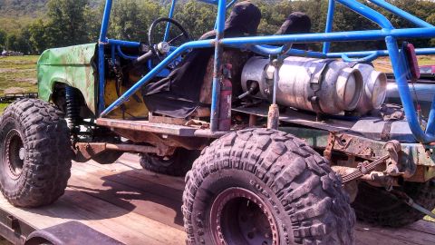 1979 Ford Bronco - A heavily modified off-road vehicle, likely a custom build based on a 1979 Ford Bronco, is parked on a wooden trailer. The vehicle features…