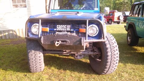 1979 Ford Bronco - The front view of a blue Ford Bronco with a winch mounted on the custom bumper. A red Jeep-like vehicle and a teal Bronco are visible in th…