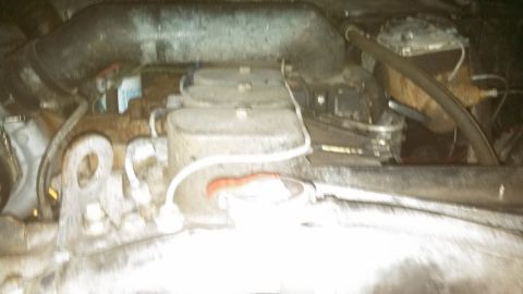 1979 Ford Bronco - This is a close-up, blurry view of an engine bay, likely from a 1979 Ford Bronco. The image shows various engine components, including hose…