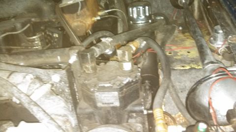 1979 Ford Bronco - This is a close-up, angled view of a vehicle's engine bay, focusing on the air conditioning compressor and associated hoses and fittings. T…