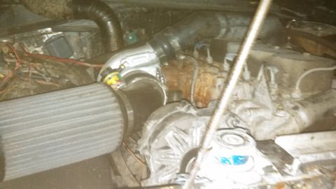 1979 Ford Bronco - A close-up view of a modified engine bay, featuring a turbocharger, large air filter, and various hoses and wiring. The engine components a…