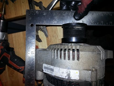 1994 Ford Bronco - Close-up of an alternator with a ruler measuring its pulley, indicating a part replacement or diagnostic process.