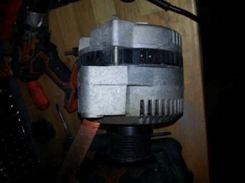 1994 Ford Bronco - An alternator is shown with a ruler for scale, resting on a wooden surface with tools nearby.