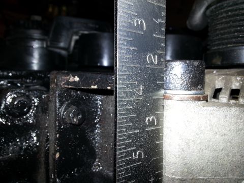 1994 Ford Bronco - Close-up of an alternator with a ruler measuring a bolt head.