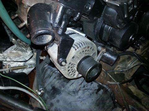 1994 Ford Bronco - Close-up view of an alternator and engine components, with a green hose attached.