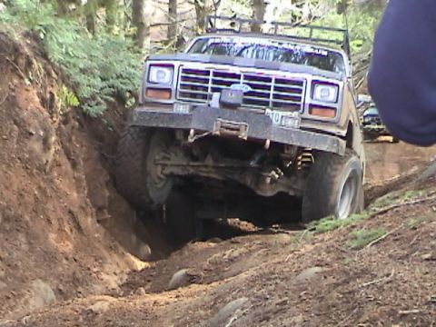 1994 Ford Explorer - This pickup truck navigates a steep dirt incline, showing its front grille and winch.