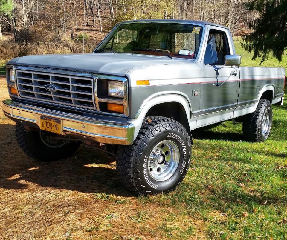 1986 Ford F-250 pickup truck, lifted with off-road tires, parked outdoors.