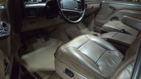 1995 Ford Bronco - The interior of a brown leather-clad vehicle, likely a 1995 Ford Bronco, is shown from the driver's side perspective. The image focuses on…