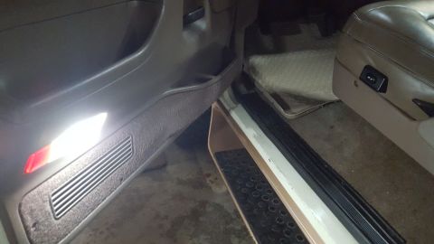 1995 Ford Bronco - The interior of a vehicle shows the driver's side door panel with a bright interior light illuminating the lower section. The seat and floo…