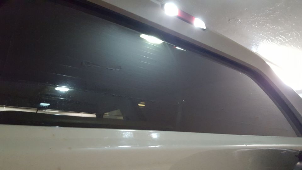 Rear window of a vehicle with a third brake light above it. Supermotors.net logo visible