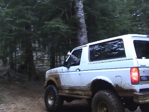1994 Ford Explorer - Mud-splattered white SUV is seen from the rear-quarter angle, with a driver giving a thumbs-up from the window.