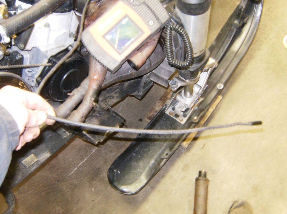 Close-up of a snowmobile engine with a hand holding a cable.