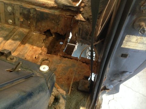 1979 Ford Bronco - This image shows severe rust damage to the floor pan and body structure of what appears to be the interior of a classic Ford Bronco. The me…