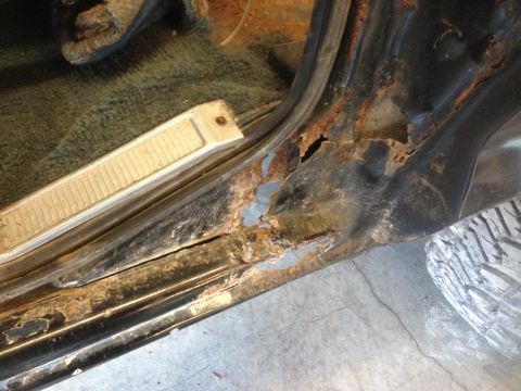 1979 Ford Bronco - The image shows severe rust damage to the rocker panel and door sill of a vehicle. The interior carpet and a door sill plate are also visib…
