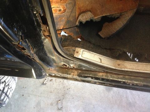 1979 Ford Bronco - This image shows extensive rust damage to the lower door frame and rocker panel of a vehicle, with interior carpet and trim also visible.