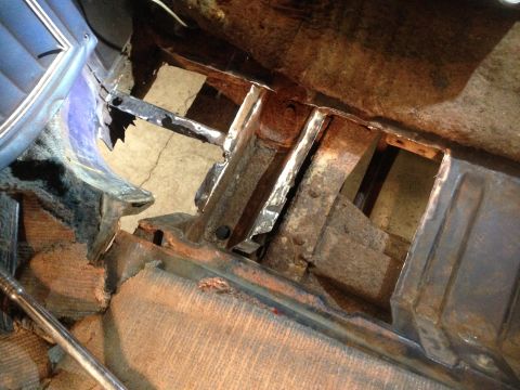 1979 Ford Bronco - The interior of a classic vehicle shows significant rust and damage to the floor pan and structural supports. A blue seat is visible on the…
