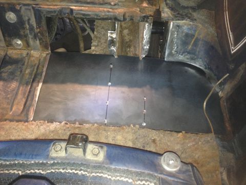 1979 Ford Bronco - A custom metal floor panel has been installed in the interior of a vehicle, secured with visible rivets. The surrounding area shows signs o…