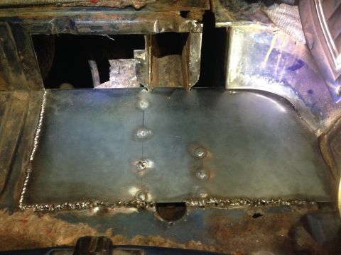 1979 Ford Bronco - A patch of sheet metal has been welded into place on the rusted floor pan of a vehicle. The welds are visible along the edges of the patch…