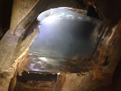 1979 Ford Bronco - A close-up view of a metal patch being welded into a rusty, angular frame structure, likely part of a vehicle's undercarriage or chassis.