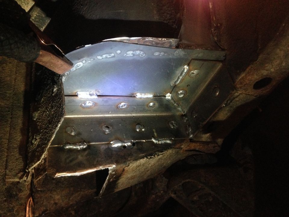 Welded metal reinforcement on a rusty vehicle frame.