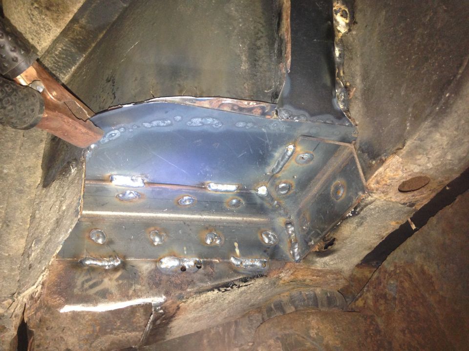 Close-up of welded metal repairs on a vehicle's undercarriage.