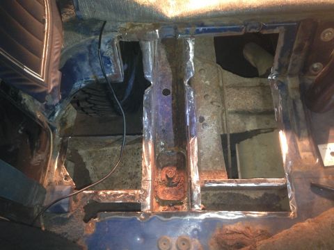 1979 Ford Bronco - This is a close-up view of the rusted-out floor pan and structural supports of a vehicle, likely undergoing restoration. The blue painted m…