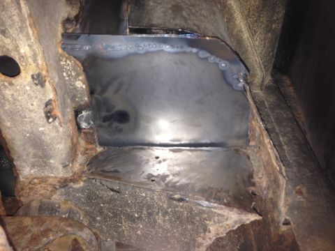 1979 Ford Bronco - A close-up view shows a section of rusted metal that has been patched with new sheet metal, likely part of a vehicle frame repair. Welds ar…