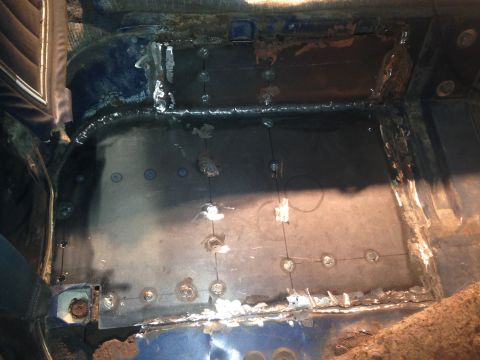 1979 Ford Bronco - The interior floor of a vehicle shows significant rust repair and welding work. A large section of the floor has been replaced with new met…