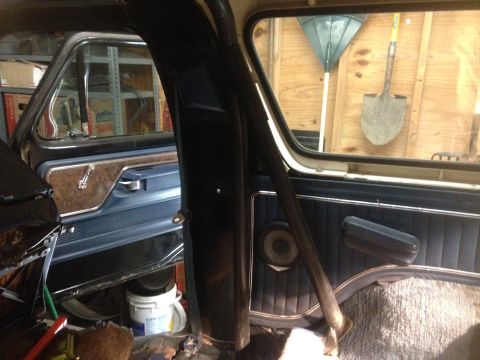 1979 Ford Bronco - Interior view of a vintage vehicle, likely a Ford Bronco, showing the driver's side door panel with wood grain trim and a roll bar. Tools l…