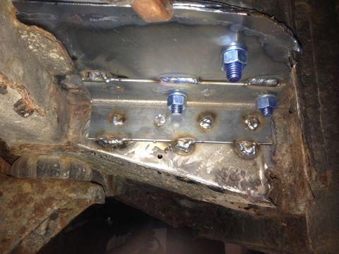 1979 Ford Bronco - This close-up photo shows a metal reinforcement plate being welded and bolted onto a rusty vehicle frame. Several blue-nutted bolts secure…