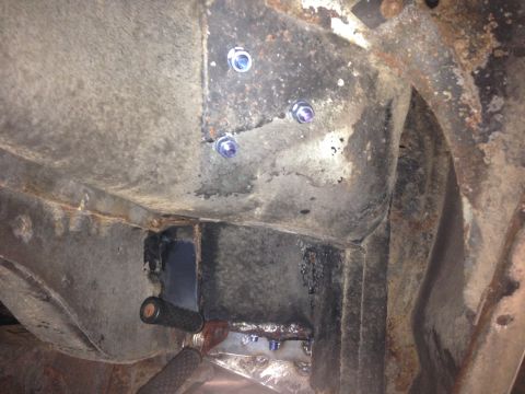 1979 Ford Bronco - Underneath view of a vehicle's frame with new bolts and welding visible. The frame appears to be heavily rusted in some areas.
