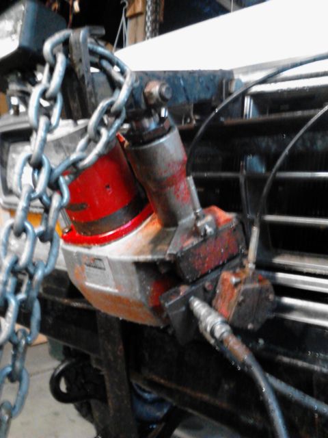 1973 Ford F-250 - A close-up view of a hydraulic cutting tool attached to the front of a vehicle, with a heavy chain also secured to the front. The tool and…