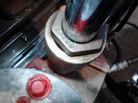1973 Ford F-250 - A close-up view of a hydraulic cylinder assembly with a large hex nut and a red cap on a metal component. The scene appears to be under the…
