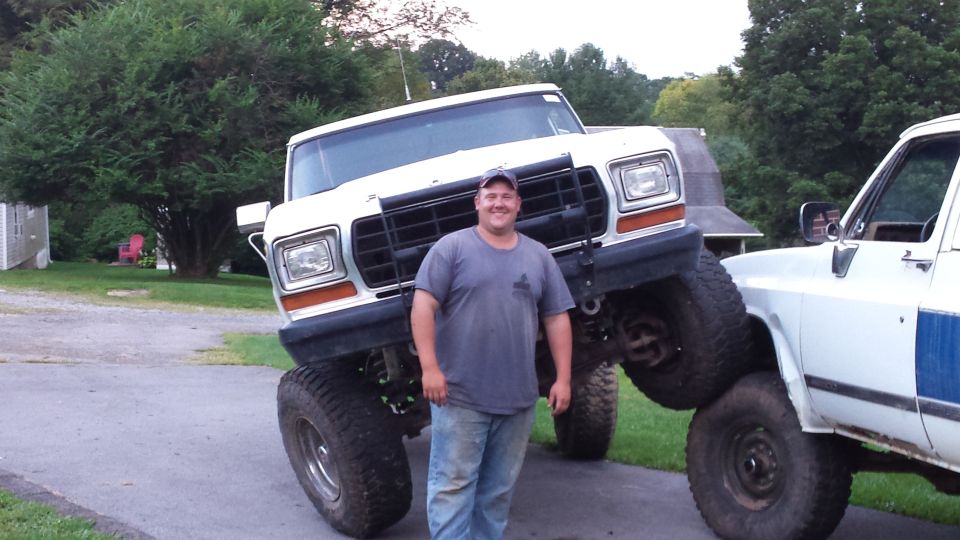 Man standing in front of a lifted white Ford Bronco, with another white truck partially visible.