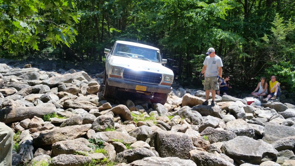 White 1970s Ford pickup truck off-roading over rocks.