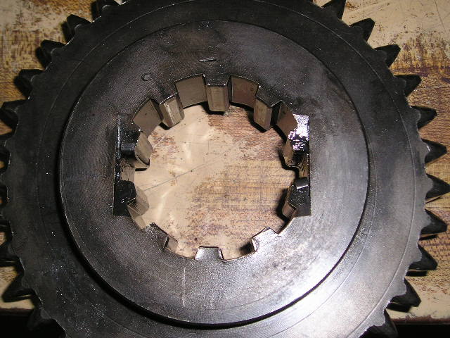 Manual transmission synchronizer slider and gear teeth on a worn wood bench